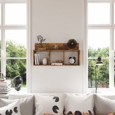 a living room filled with lots of furniture next to two large windows on top of a white wall