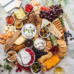 an assortment of cheeses, crackers and olives arranged on a platter