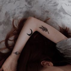 a woman laying on the floor with her back turned to the camera and tattoos on her arm