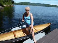 an older woman standing on the front end of a small boat