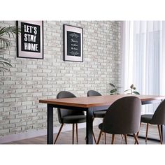 a dining room table with four chairs next to a brick wall