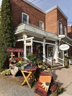 an outside view of a flower shop with flowers and plants on the tables in front