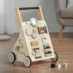 a wooden toy with various items on it sitting on the floor next to a chair