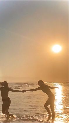 two people holding hands on the beach at sunset