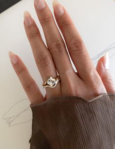 a woman's hand with a ring on top of her finger and a drawing in the background