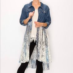 a woman standing in front of a white wall wearing black leggings and a denim jacket