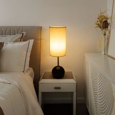 a bedroom with a bed, night stand and lamp on the bedside table next to it