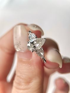 a woman's hand holding an engagement ring with two diamonds on top of it