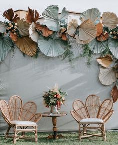 two chairs and a table with flowers on them in front of a wall decorated with umbrellas