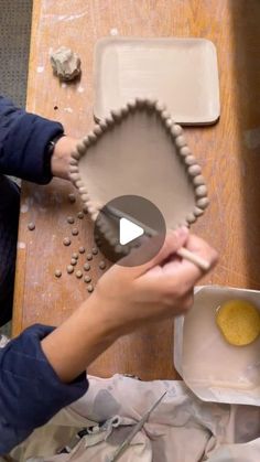 a person is making a cookie in the shape of a heart and holding a rolling pin