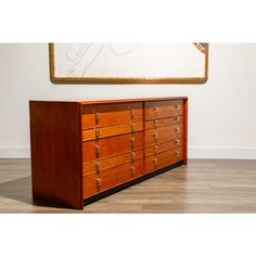 a large wooden dresser sitting on top of a hard wood floor next to a painting