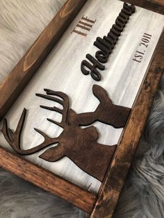 a wooden sign with deer silhouettes and the words hunting life on it, sitting on a fur rug