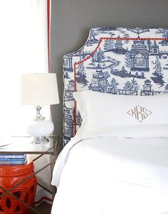 an image of a bed with white linens and red accents on the headboard