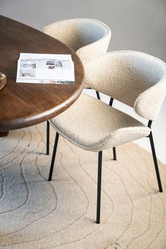 two chairs sitting on top of a rug next to a table with a magazine on it