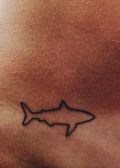 a small tattoo on the back of a man's stomach that has a shark drawn on it