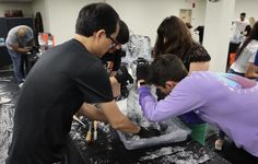 two men and a woman are working on something in an ice sculpture at the event