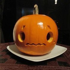 a carved pumpkin sitting on top of a white plate with holes in it's face