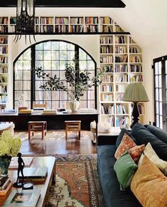 a living room filled with lots of furniture and bookshelves next to a window