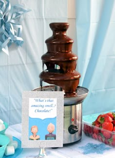 a chocolate fountain with a card on it and some strawberries in the foreground