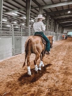 a man riding on the back of a brown horse in an indoor arena at a rodeo