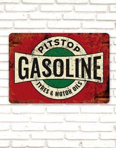 a red and green sign on a white brick wall that says,'gasline tires & motor oils '