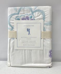 a white sheet with purple flowers on it and a label that says butterfliple