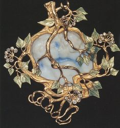 a brooch with leaves and vines on it's side, hanging from a black background