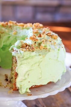 a piece of cake with green frosting and nuts on top is sitting on a plate