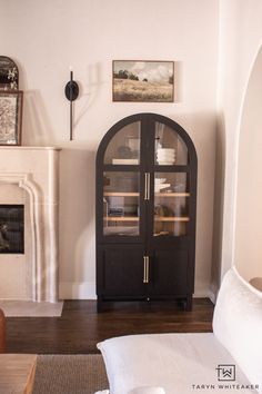 a living room with a white couch and black bookcase next to a fire place