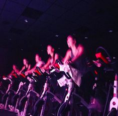 there are many bikes lined up in the dark room with people riding on one bike