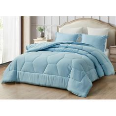 a bed with blue comforter and pillows on it in a room next to a window