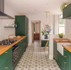 a kitchen with green cabinets and tiled flooring next to a stove top oven in the center