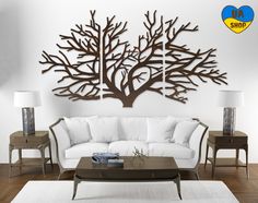 a living room with white furniture and a large metal tree wall art on the wall