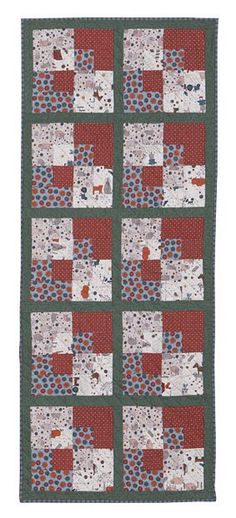 a quilted wall hanging with red and white squares