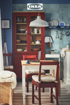 a kitchen with blue walls and wooden flooring, including a dining room table surrounded by chairs