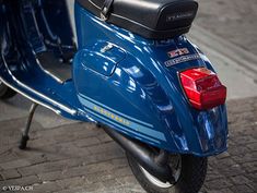 the back end of a blue scooter parked on a sidewalk