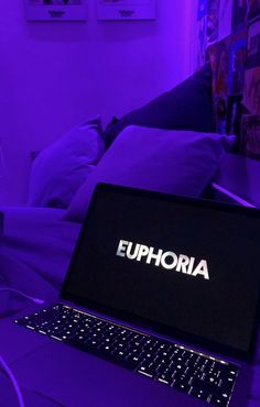 an open laptop computer sitting on top of a purple lit bed with the word euphoria printed on it