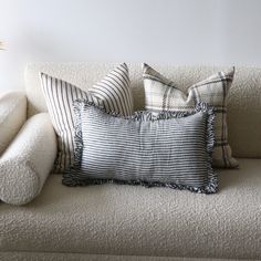 a white couch with pillows on it and a plant in the corner next to it