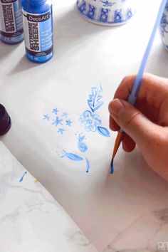 someone is drawing with blue ink on a white surface