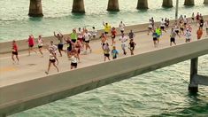 a group of people running on a bridge over water