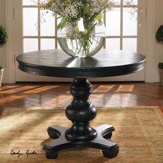 a table with flowers in a vase on top of it, sitting next to a window