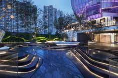 an empty swimming pool in the middle of a large city at night with lights on it