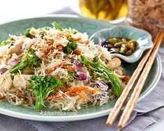 a green plate topped with rice, broccoli and carrots next to chopsticks