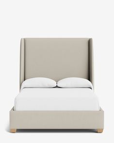 an upholstered bed with two pillows on it