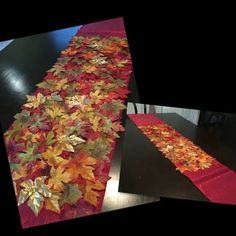 the table runner is decorated with autumn leaves and red satin runners are laid on top of each other