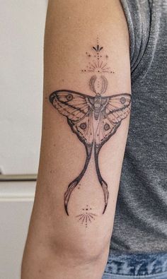 a woman's arm with a moth tattoo on it