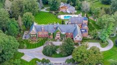 an aerial view of a large home surrounded by trees and grass with a pool in the middle