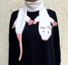 a woman wearing a sweater with two mice on it's shoulders and a scarf around her neck