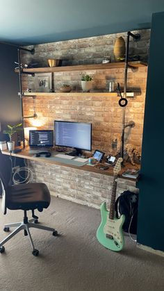 a desk with a guitar, monitor and keyboard