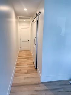 an empty hallway with white walls and wooden floors